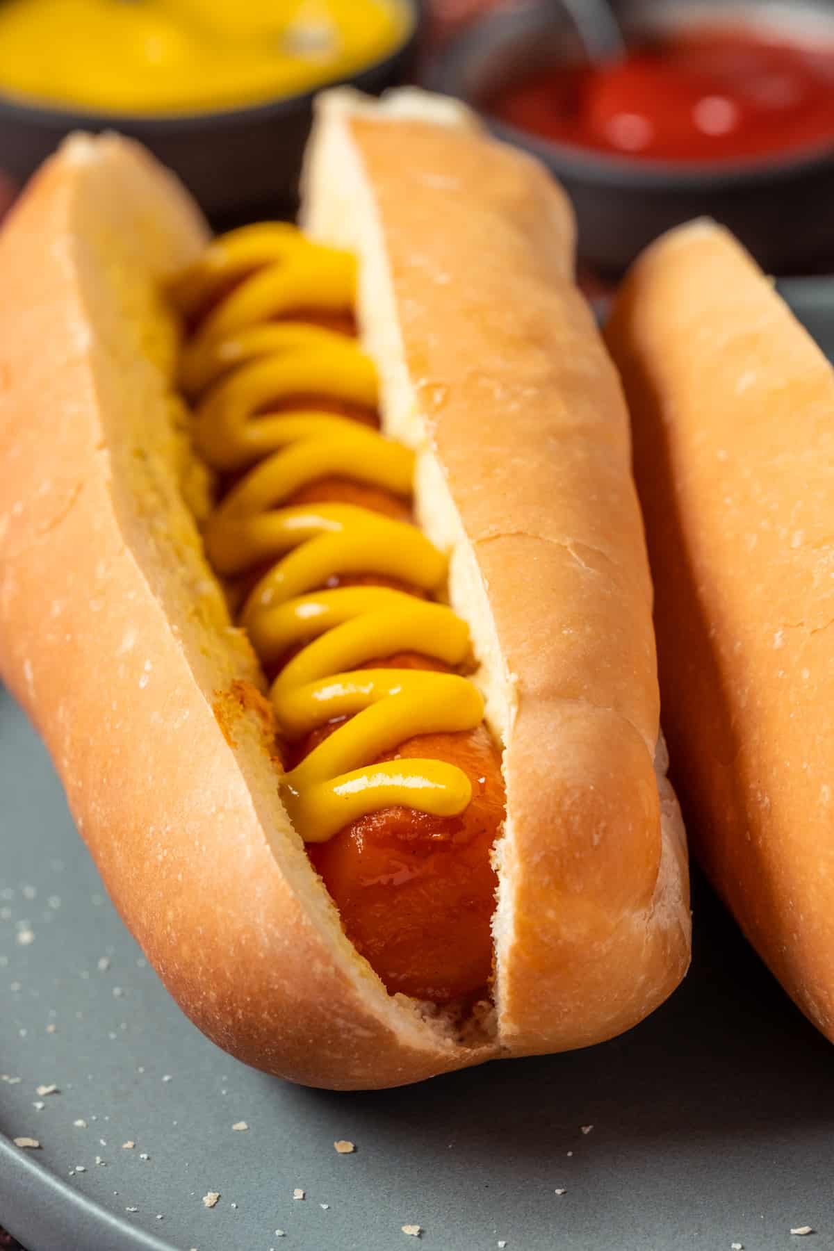 Carrot dogs with mustard on a gray plate.