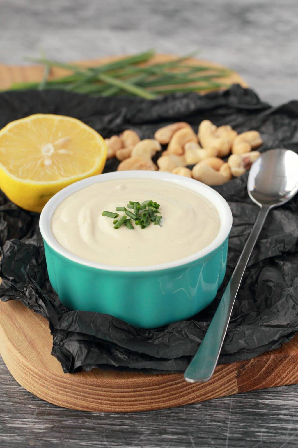 Cashew cream in a turquoise and white ramekin with chopped chives on top. 