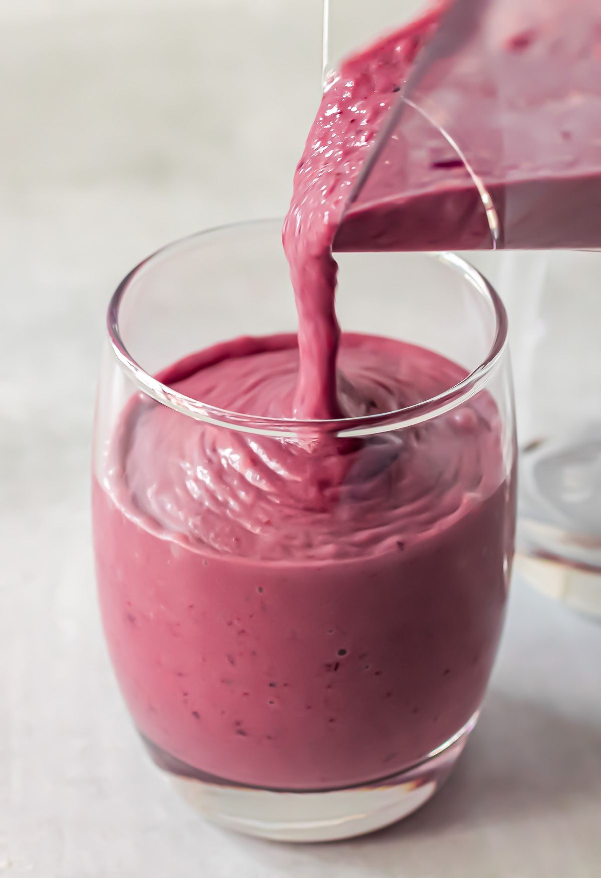 Cherry smoothie pouring from the blender jug into a glass.