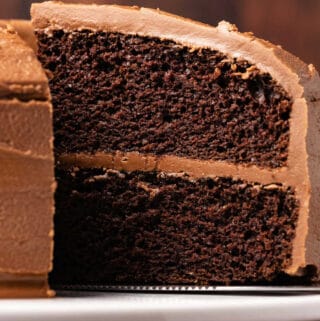 Vegan chocolate cake on a white cake stand.