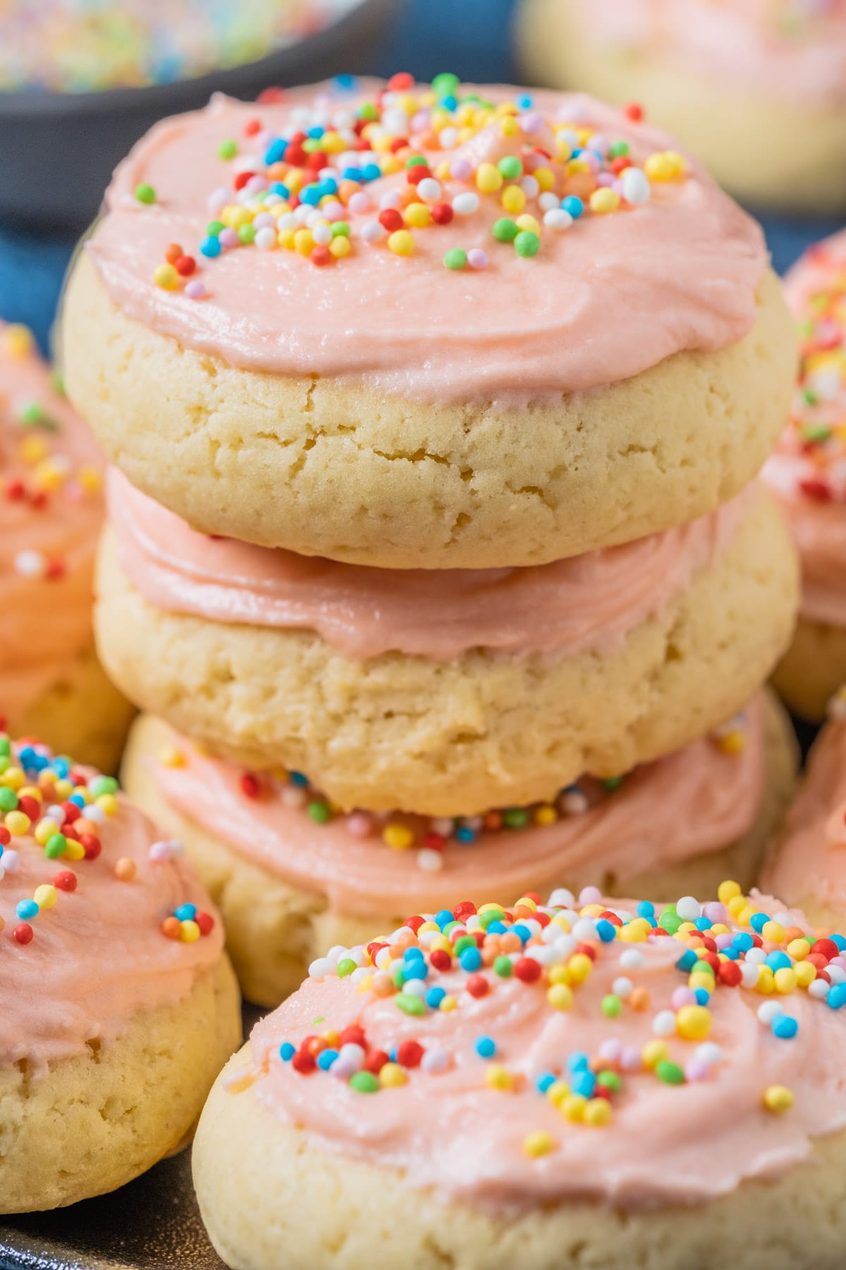 Frosted vegan sugar cookies stacked up on a plate. 