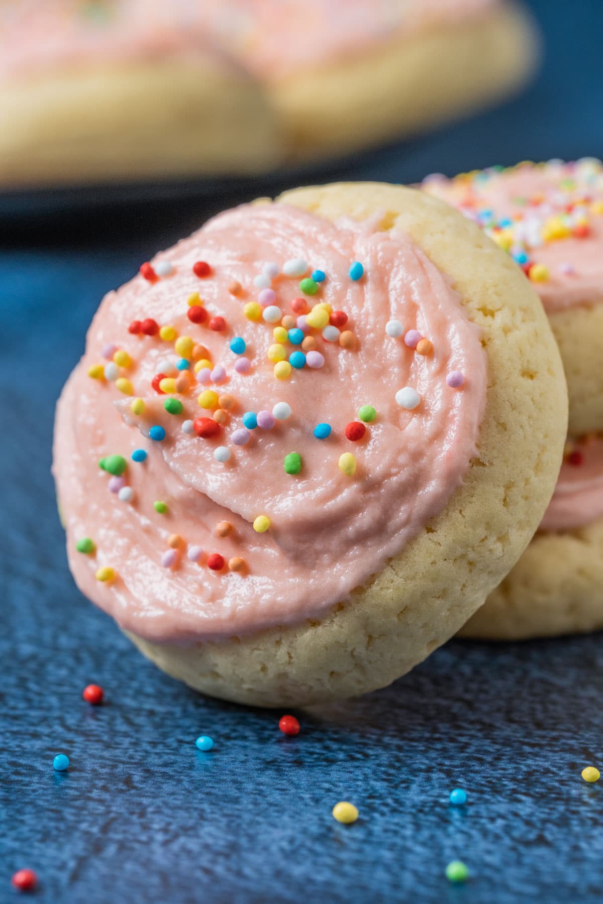 Frosted sugar cookie leaning against a stack of cookies.