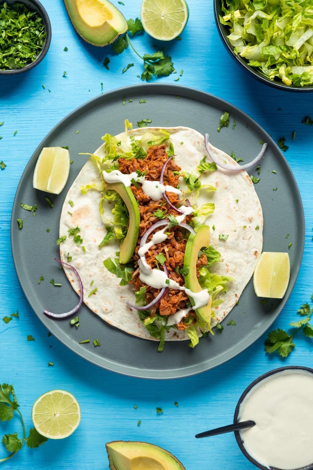 Assembling jackfruit tacos on a gray plate.