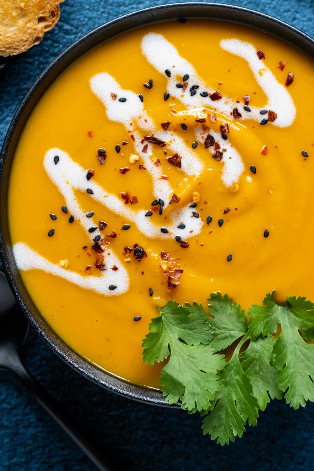 Thai sweet potato soup in a black bowl topped with fresh cilantro.