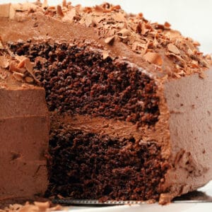 Vegan chocolate cake on a white cake stand.