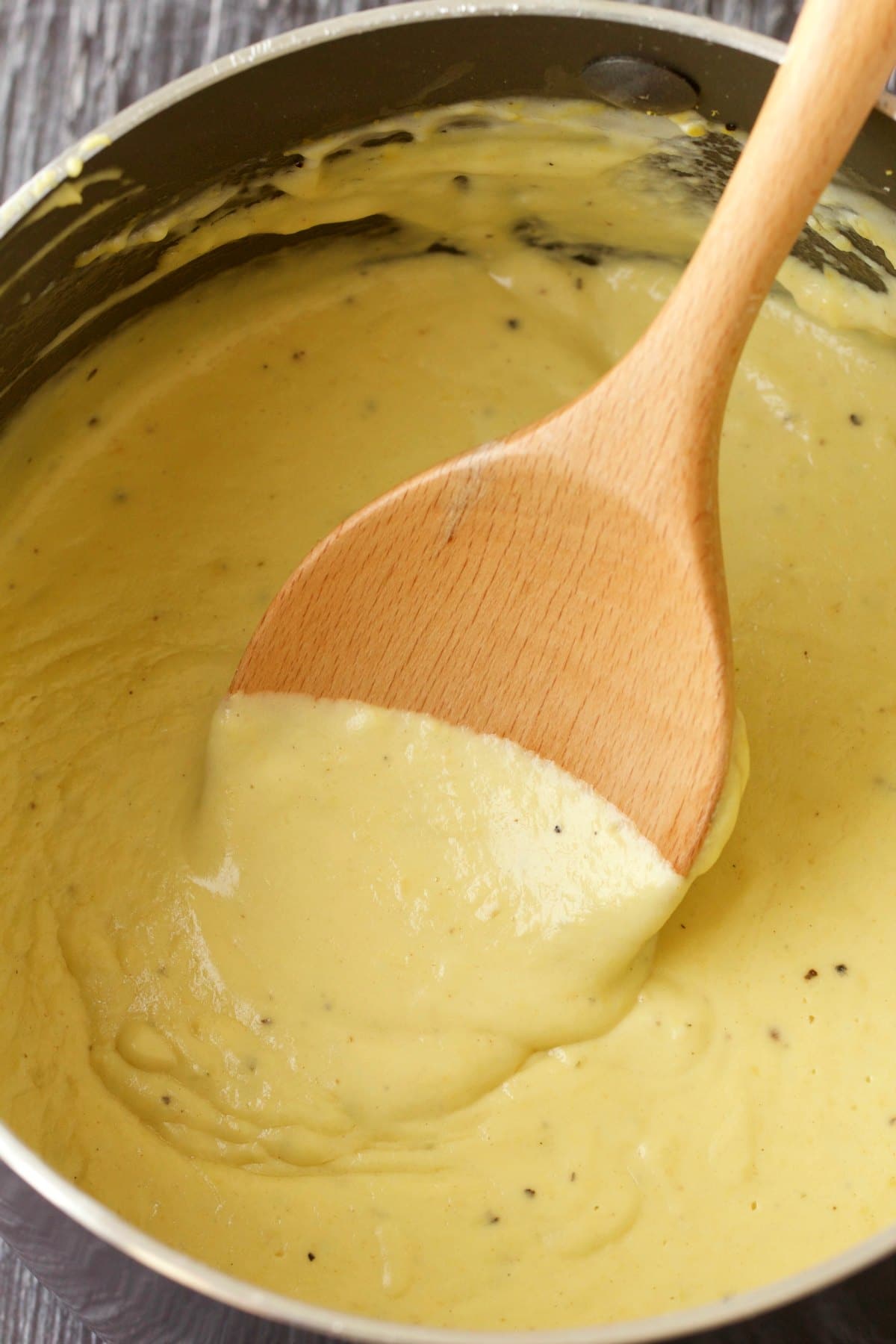 Vegan alfredo sauce in a saucepan with a wooden spoon. 