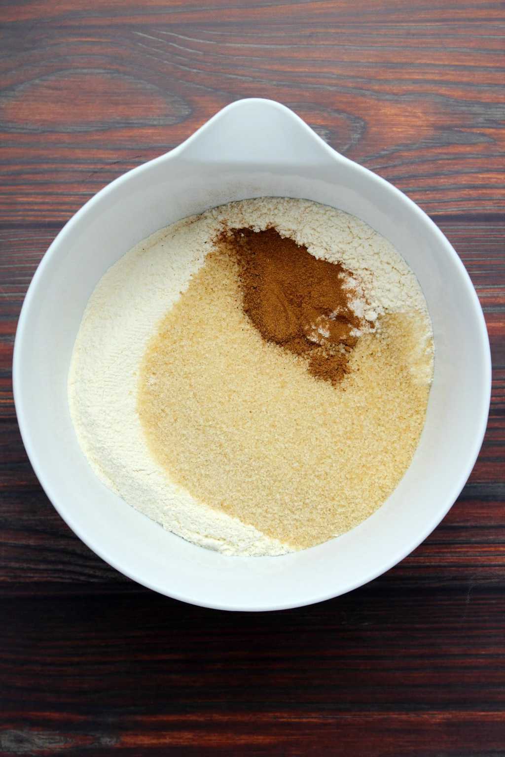 Dry ingredients for a vegan apple cake in a white mixing bowl. 