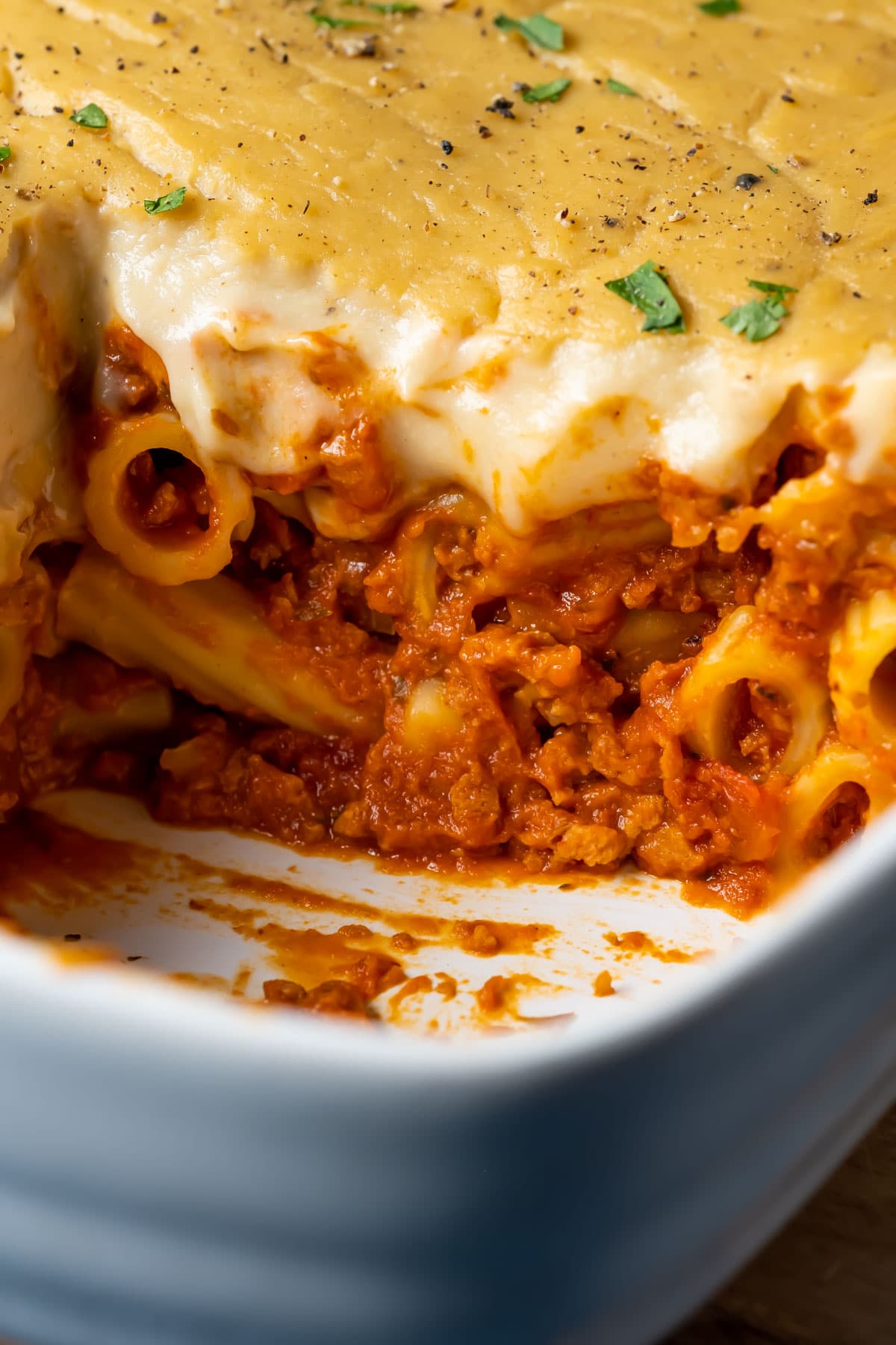 Vegan baked ziti with one slice removed, in a white dish.