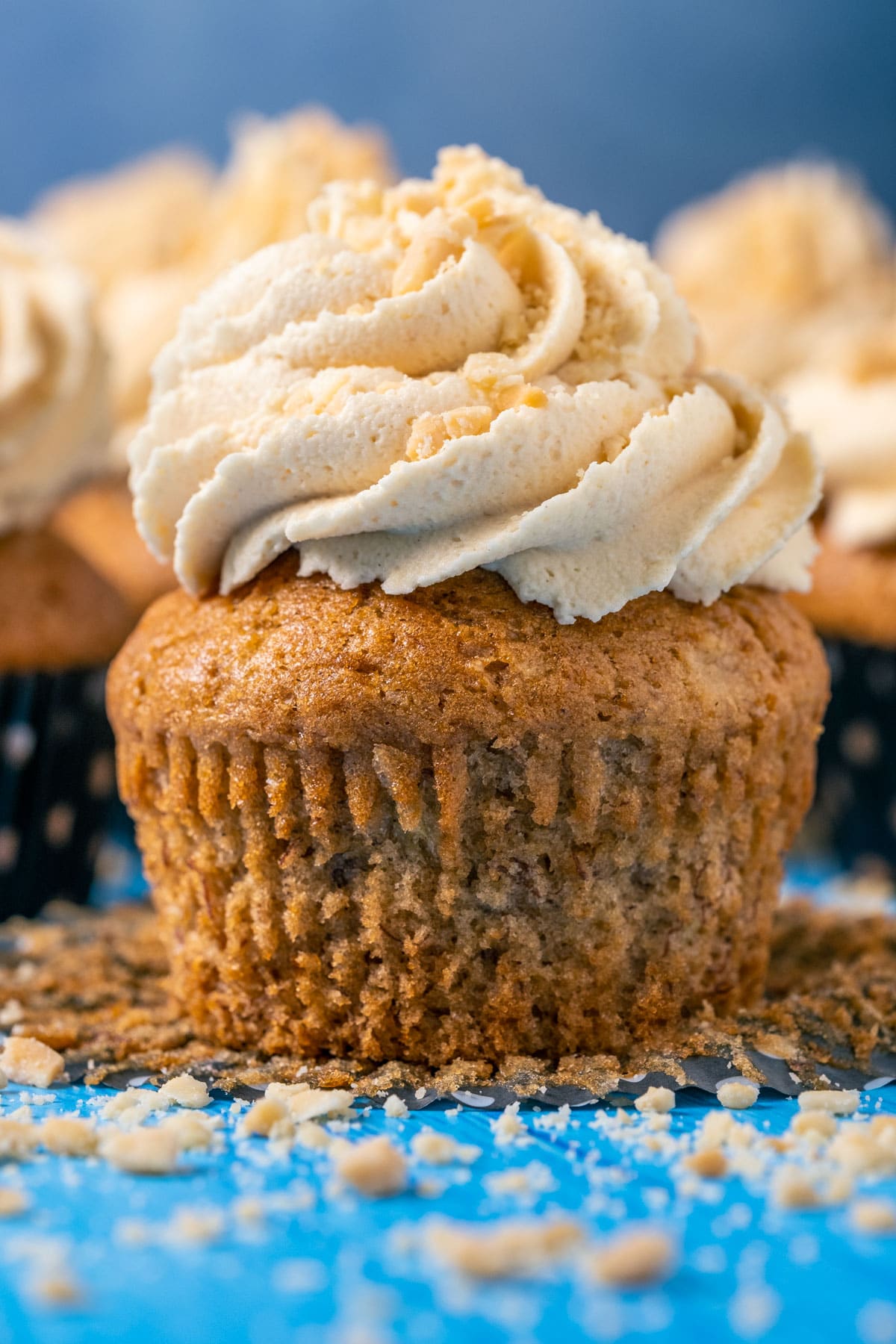 Frosted vegan banana cupcake with the liner pulled down.