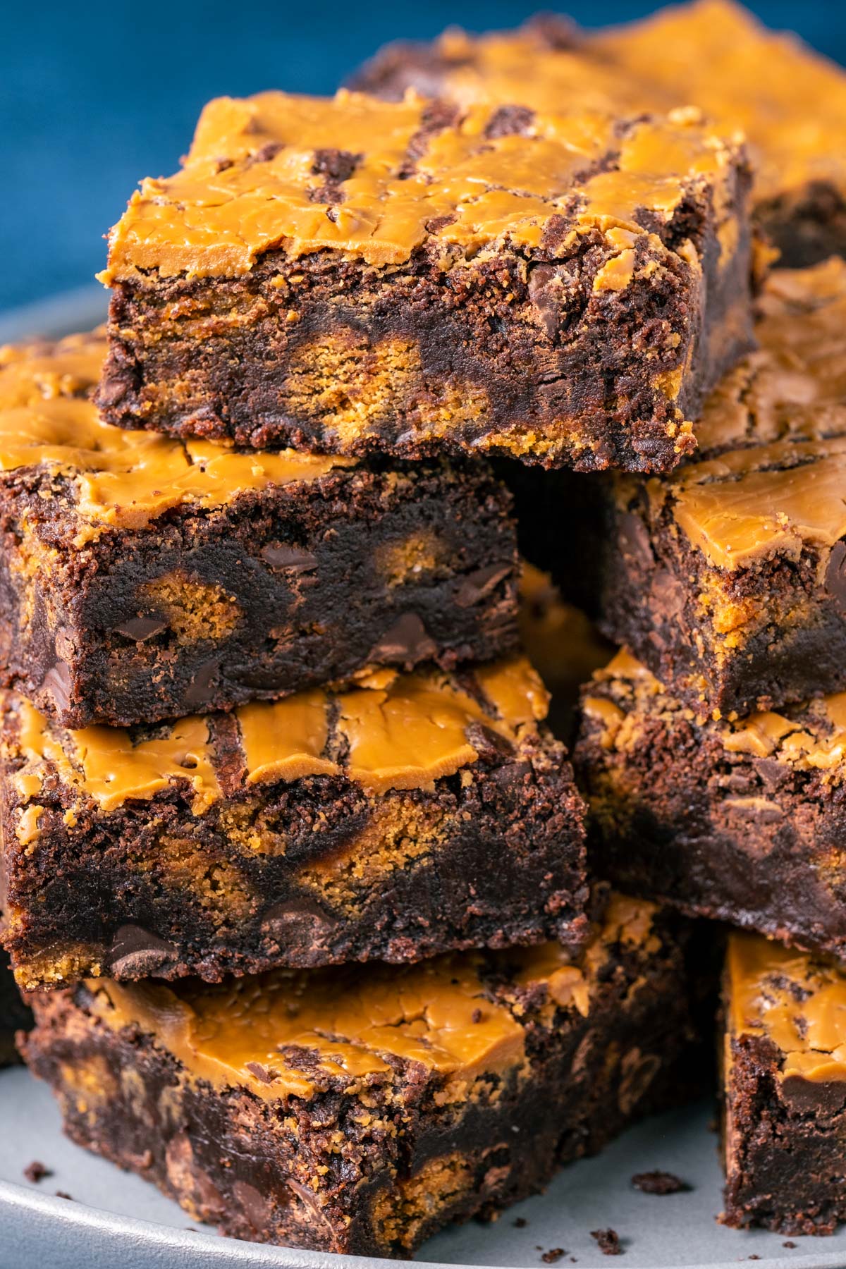 Vegan biscoff brownies roughly stacked up on a plate. 