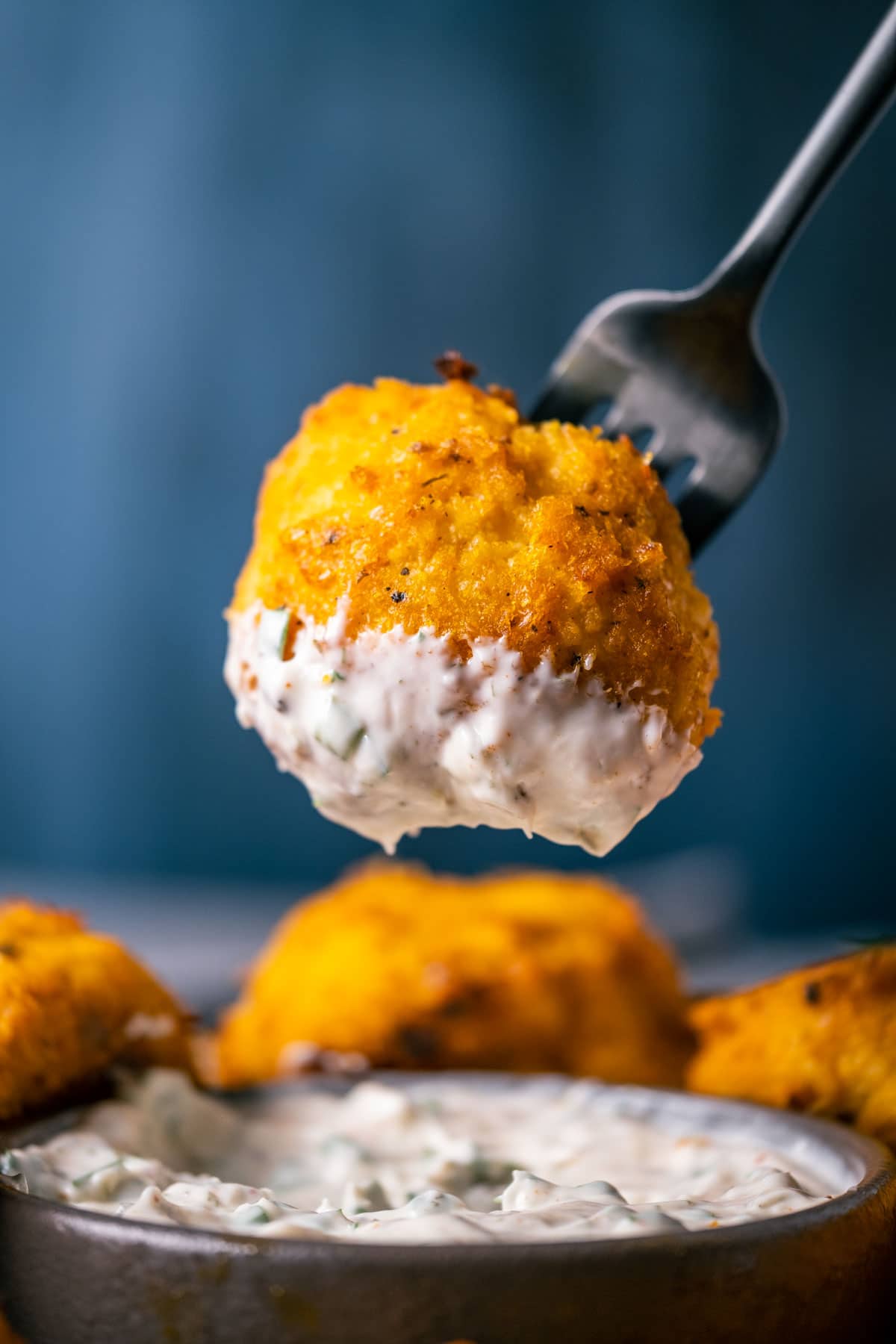 Buffalo cauliflower dipped in ranch dressing on a fork.