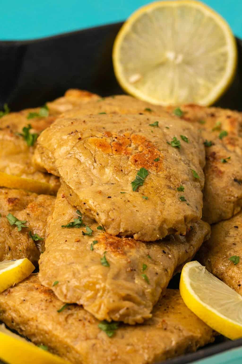 Vegan chicken fillets topped with chopped parsley and fresh lemon slices. 