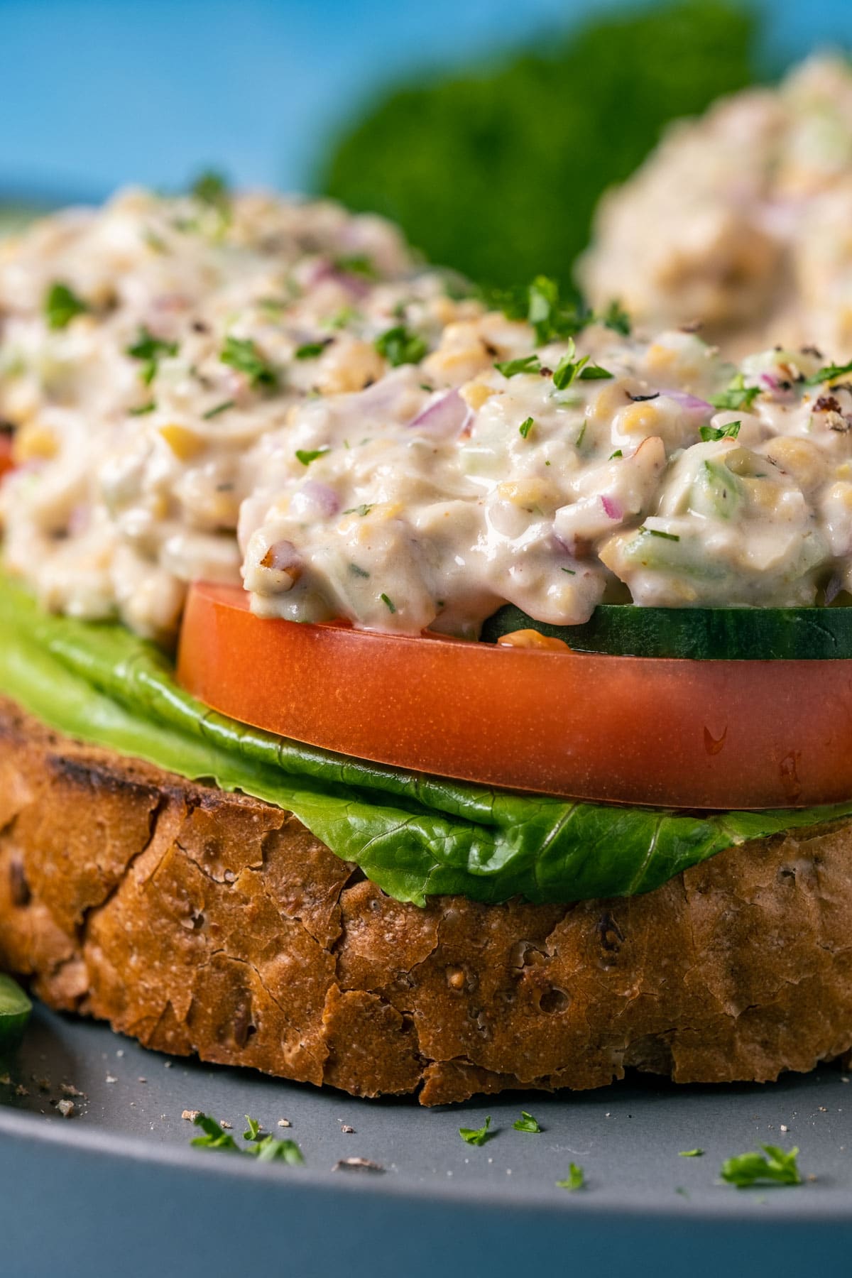 Open faced sandwiches topped with vegan chicken salad on a gray plate.