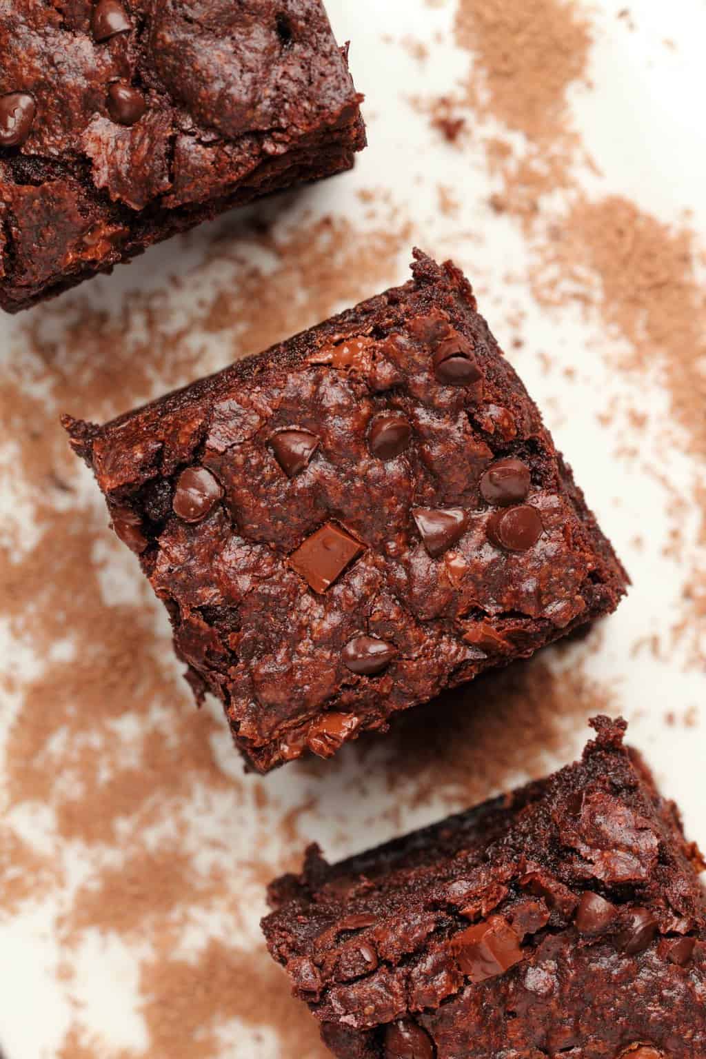 Vegan chocolate brownies stacked up on a white plate. 