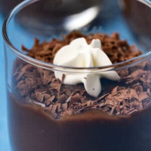 Vegan chocolate pudding topped with chocolate shavings and vegan whipped cream in a glass.