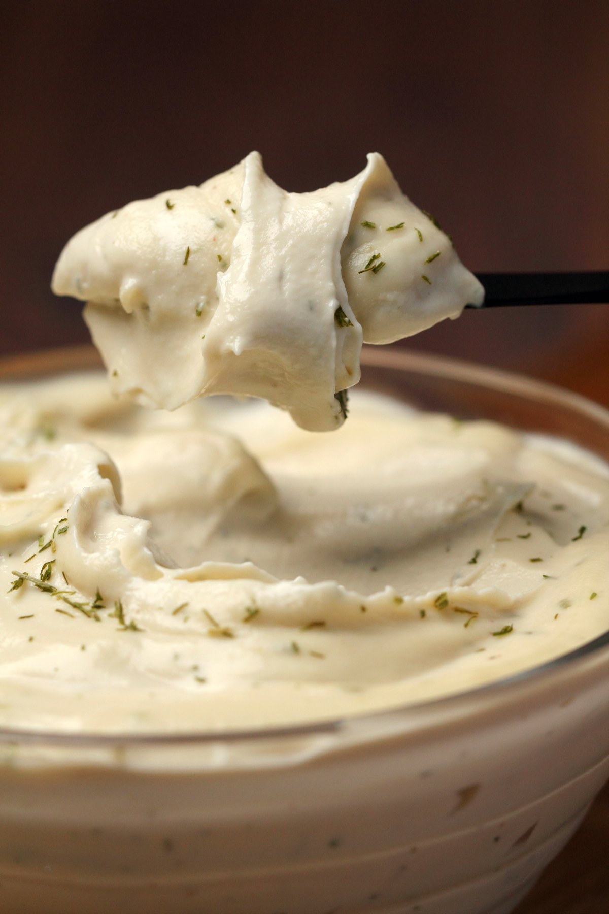 Vegan cream cheese in a glass bowl with a knife. 