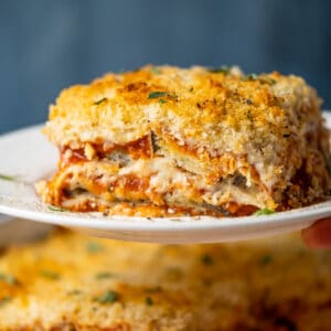 Slice of vegan eggplant parmesan on a white plate.