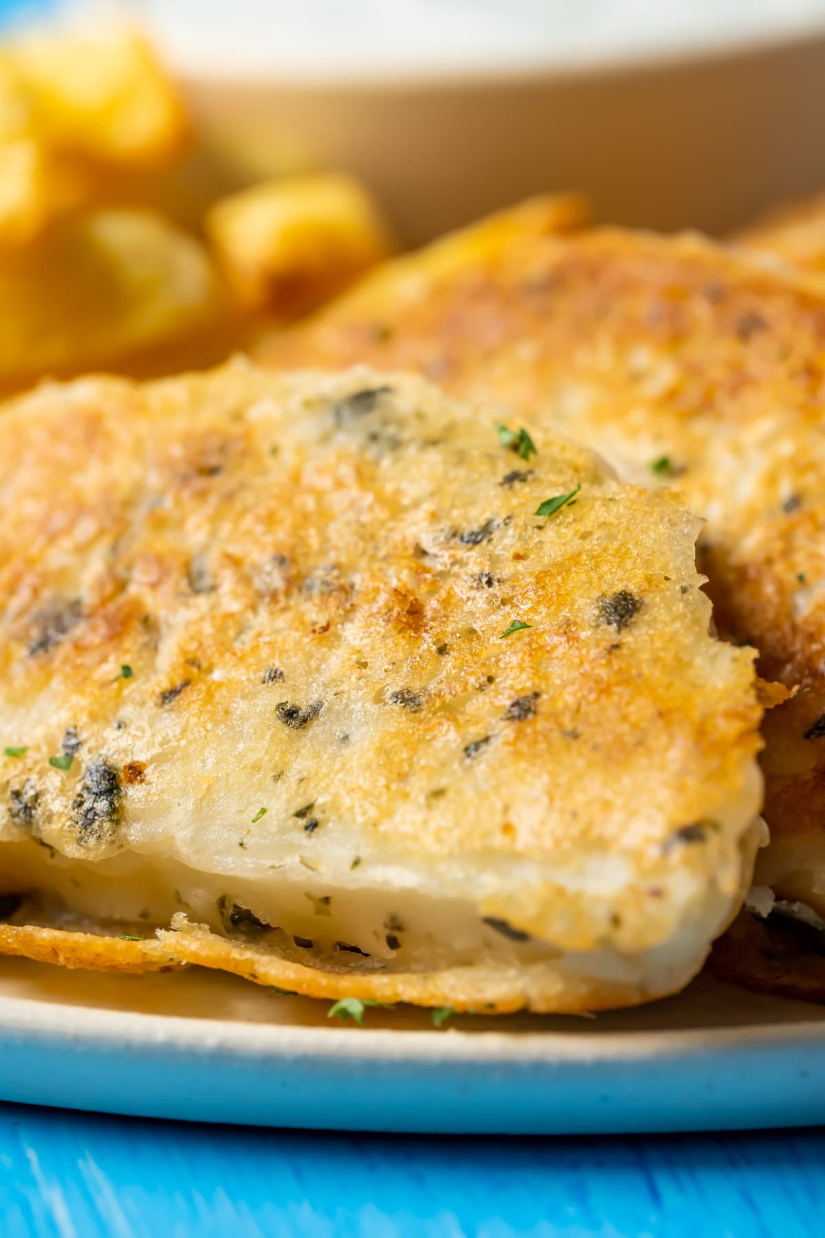 Beer battered vegan fish with chips, vegan tartar sauce and fresh lemon on a plate.