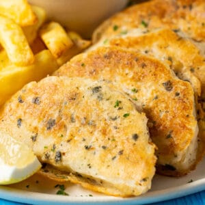 Beer battered vegan fish with chips and tartar sauce on a plate.