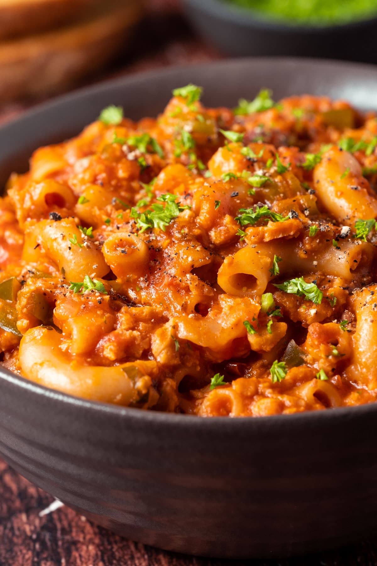 Vegan goulash with fresh chopped parsley in a brown bowl.