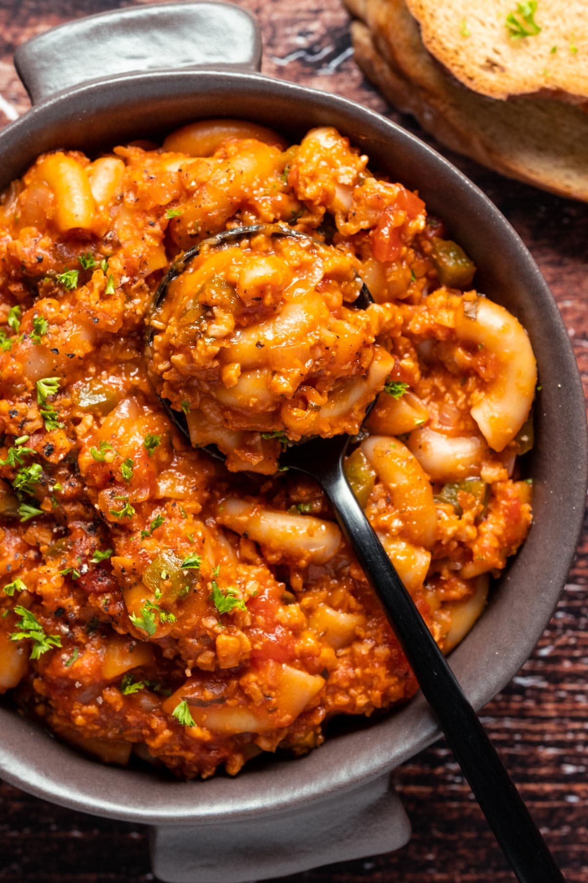 Vegan goulash in a brown bowl with a spoon.