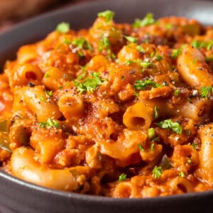 Vegan goulash with fresh parsley in a brown bowl.