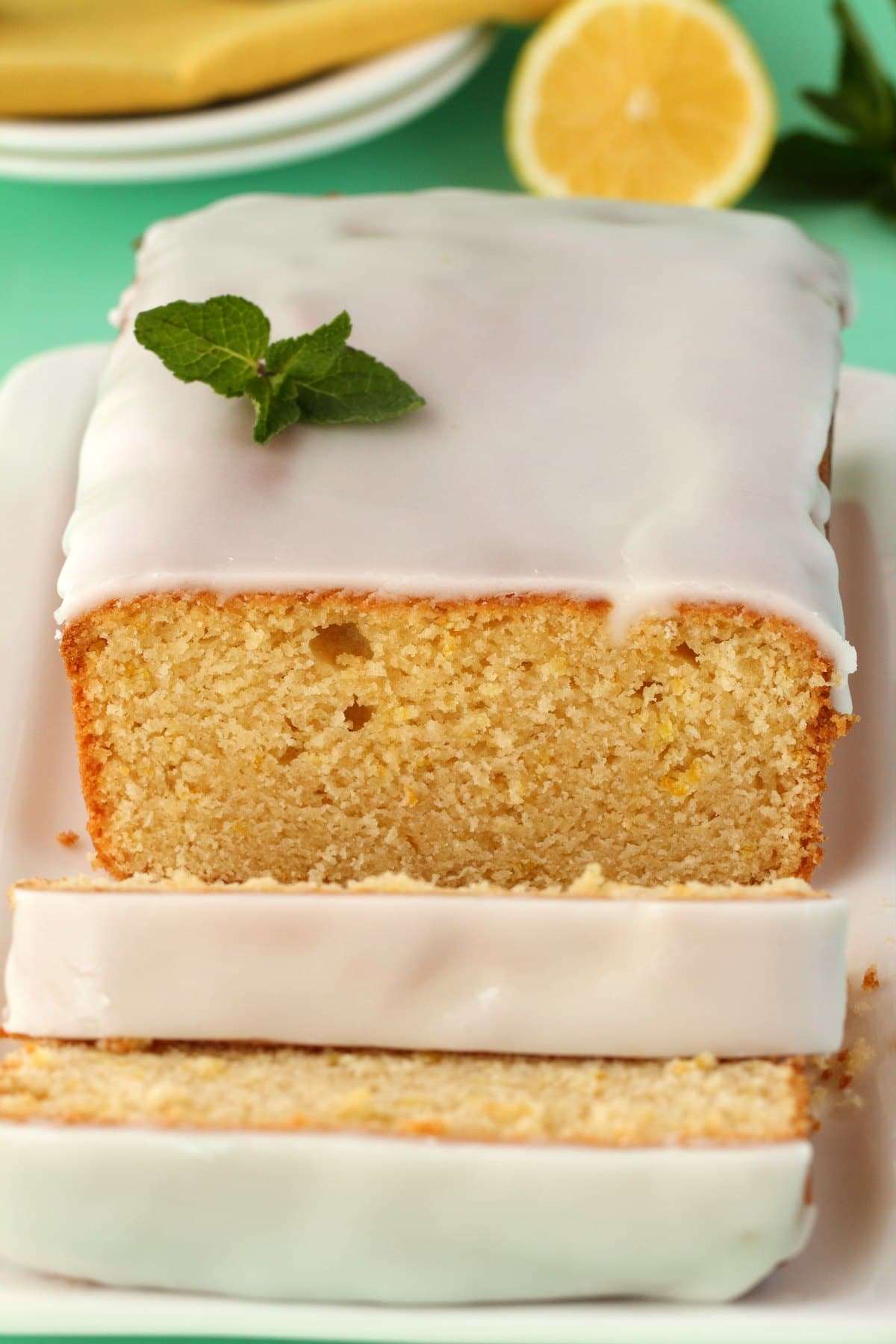 Vegan lemon pound cake topped with lemon glaze on a white plate. 