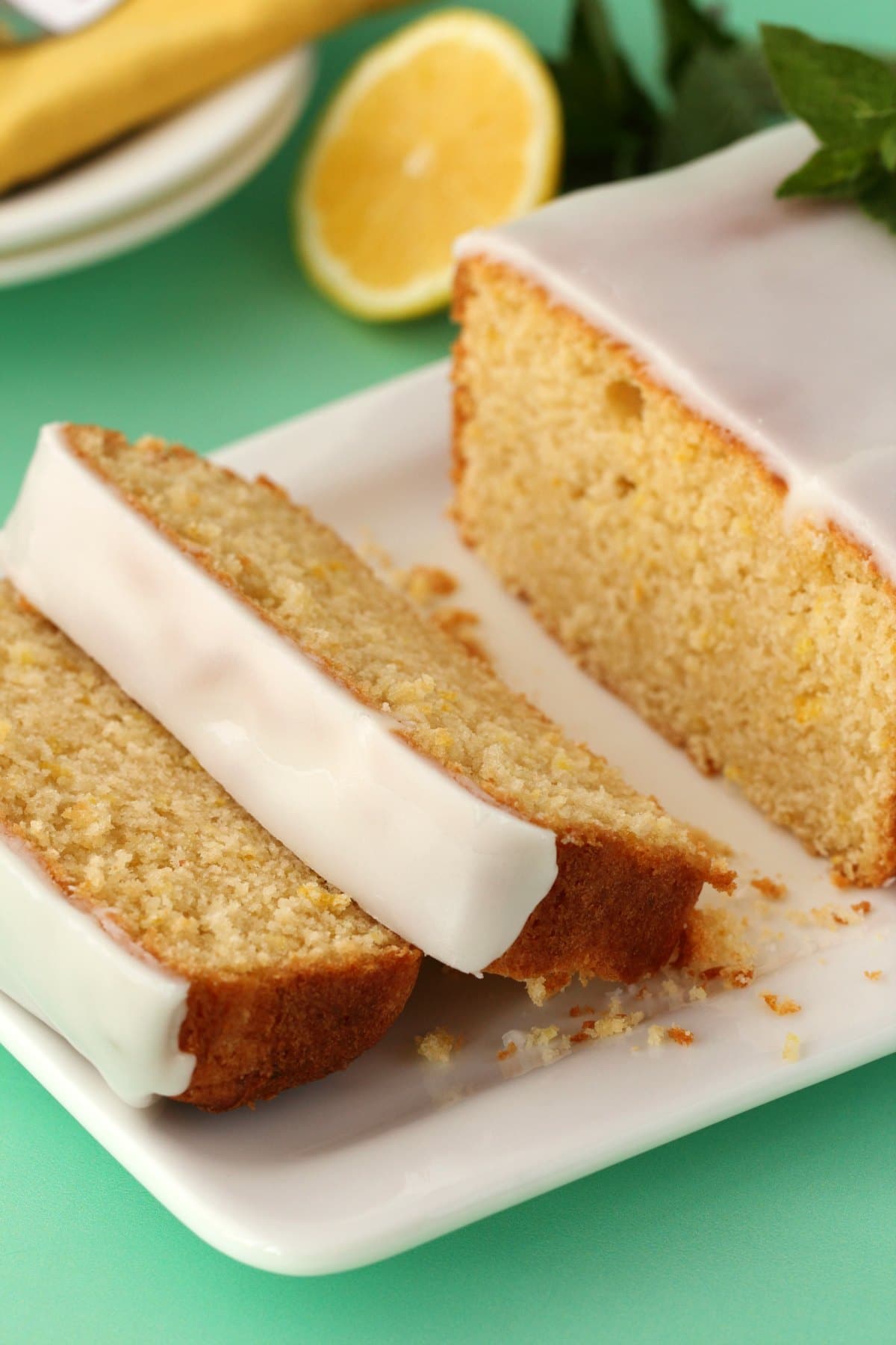 Sliced lemon pound cake topped with a lemon glaze, on a white plate. 