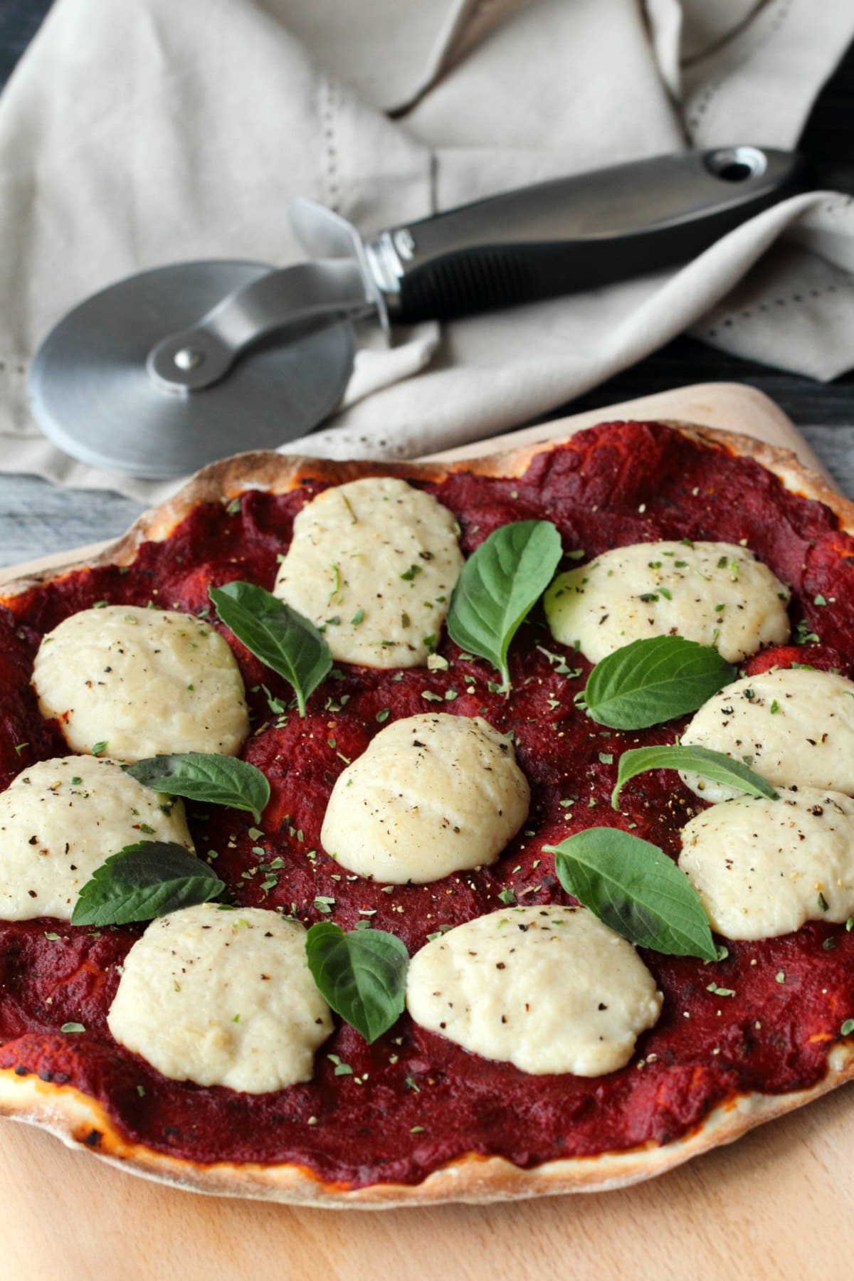 Vegan Mozzarella melted on top of a pizza with fresh basil leaves.