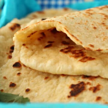 Vegan naan in a basket with the top naan folded in half.