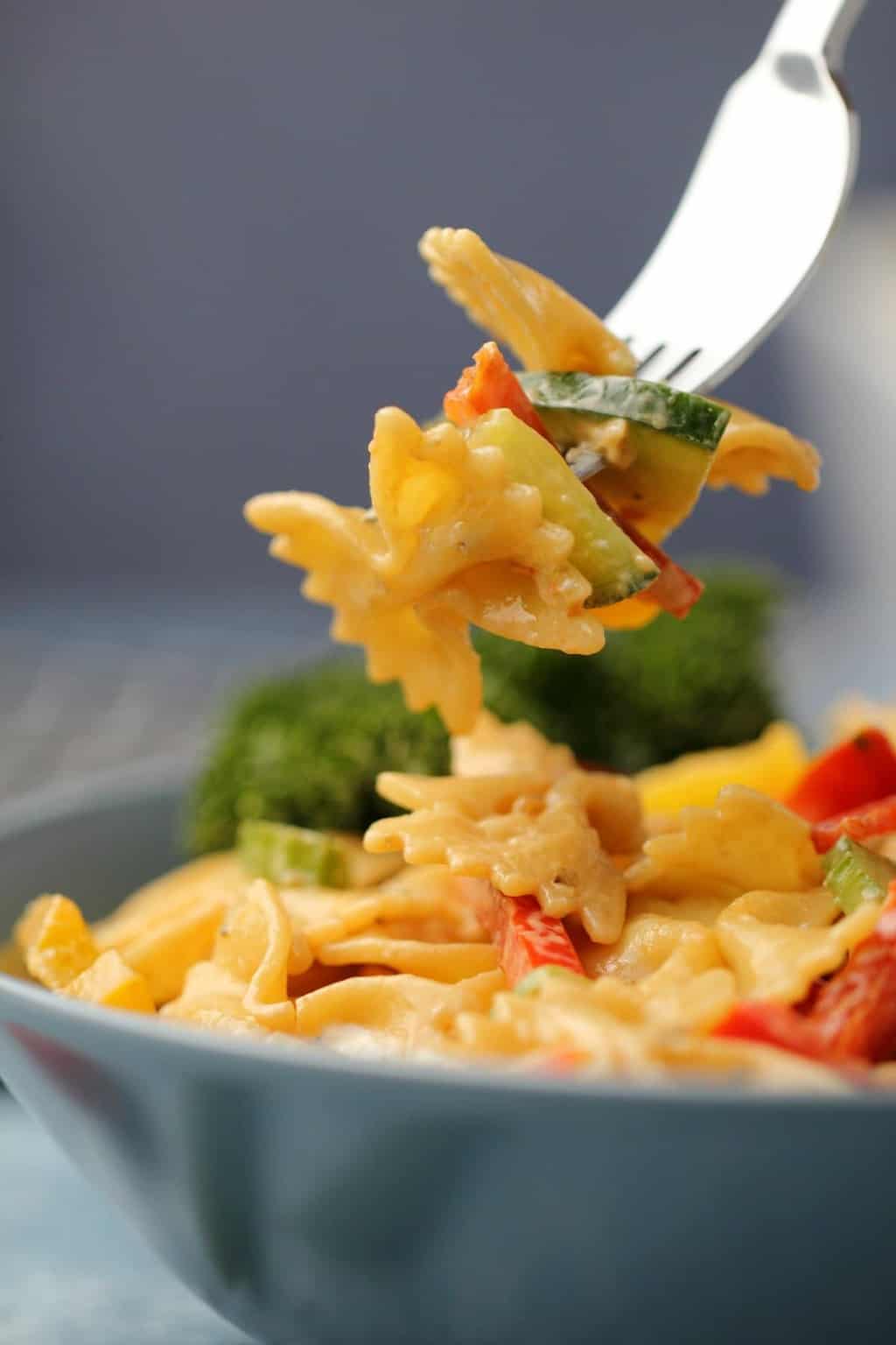 Vegan pasta salad in a blue bowl with a fork. 