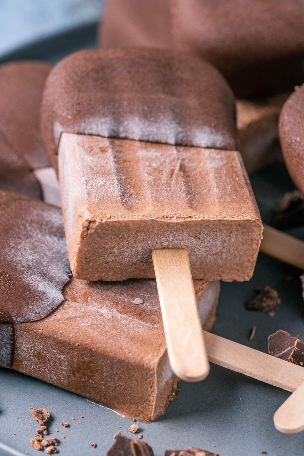 Chocolate dipped popsicles stacked up on a plate.