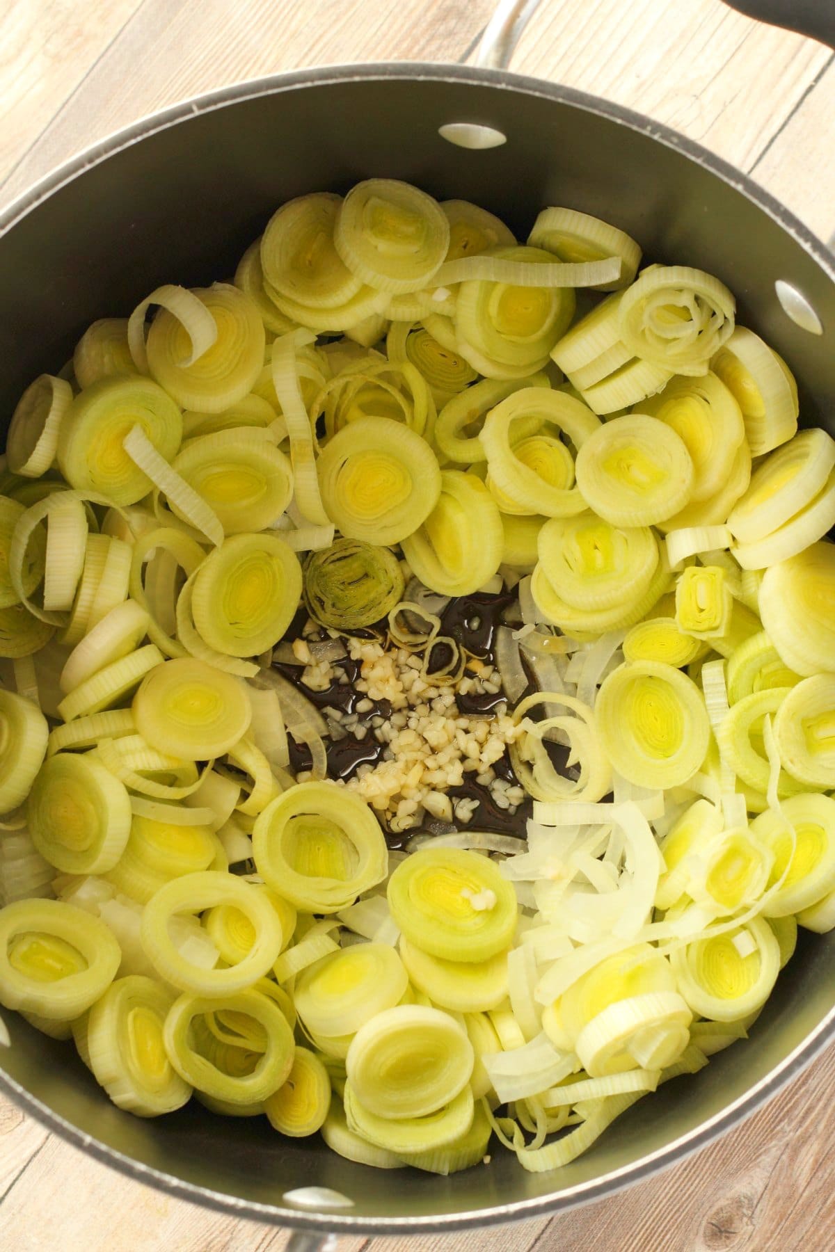 Chopped onions and leeks with crushed garlic and olive in a pot. 