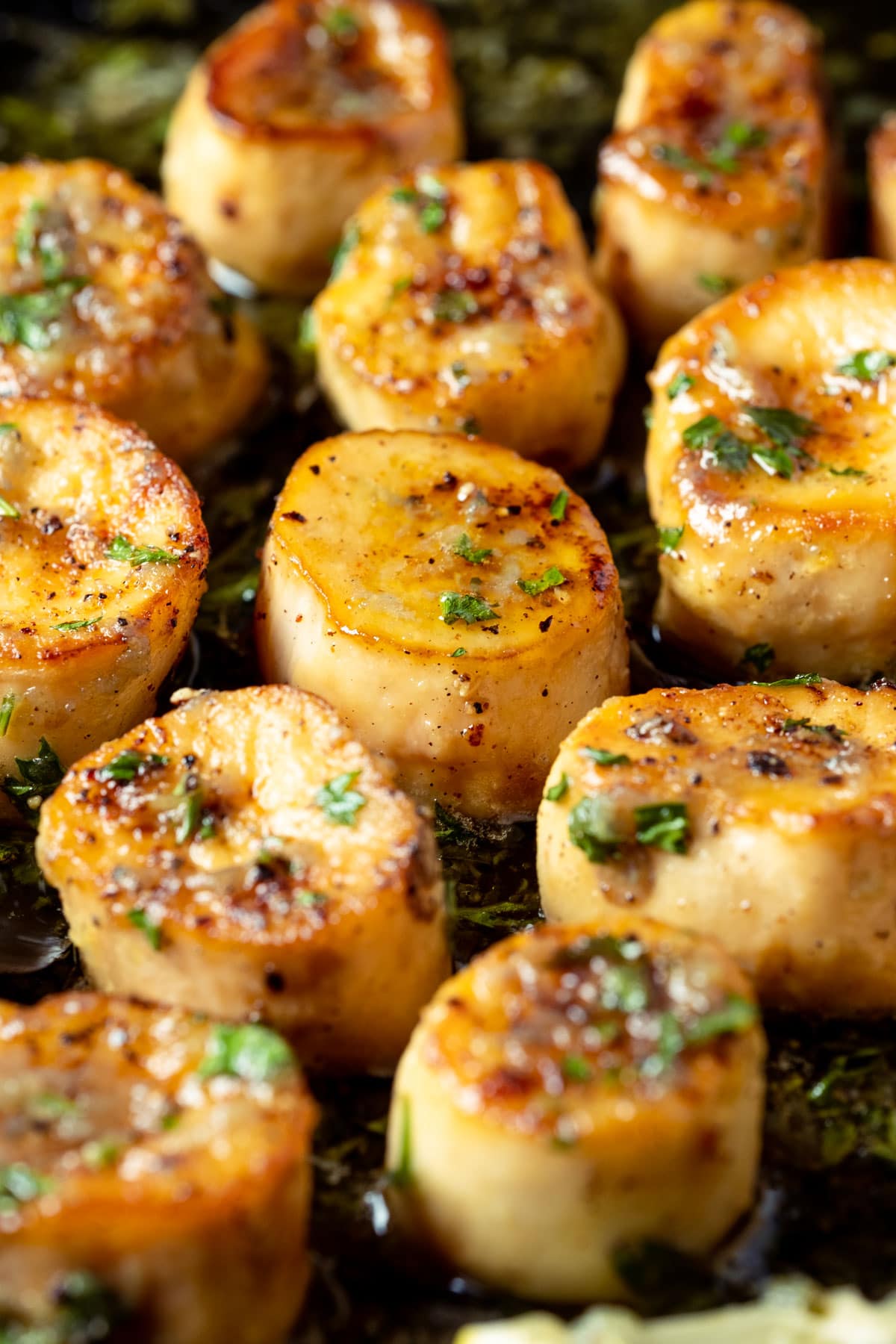 Vegan scallops with lemon slices and parsley in a frying pan.