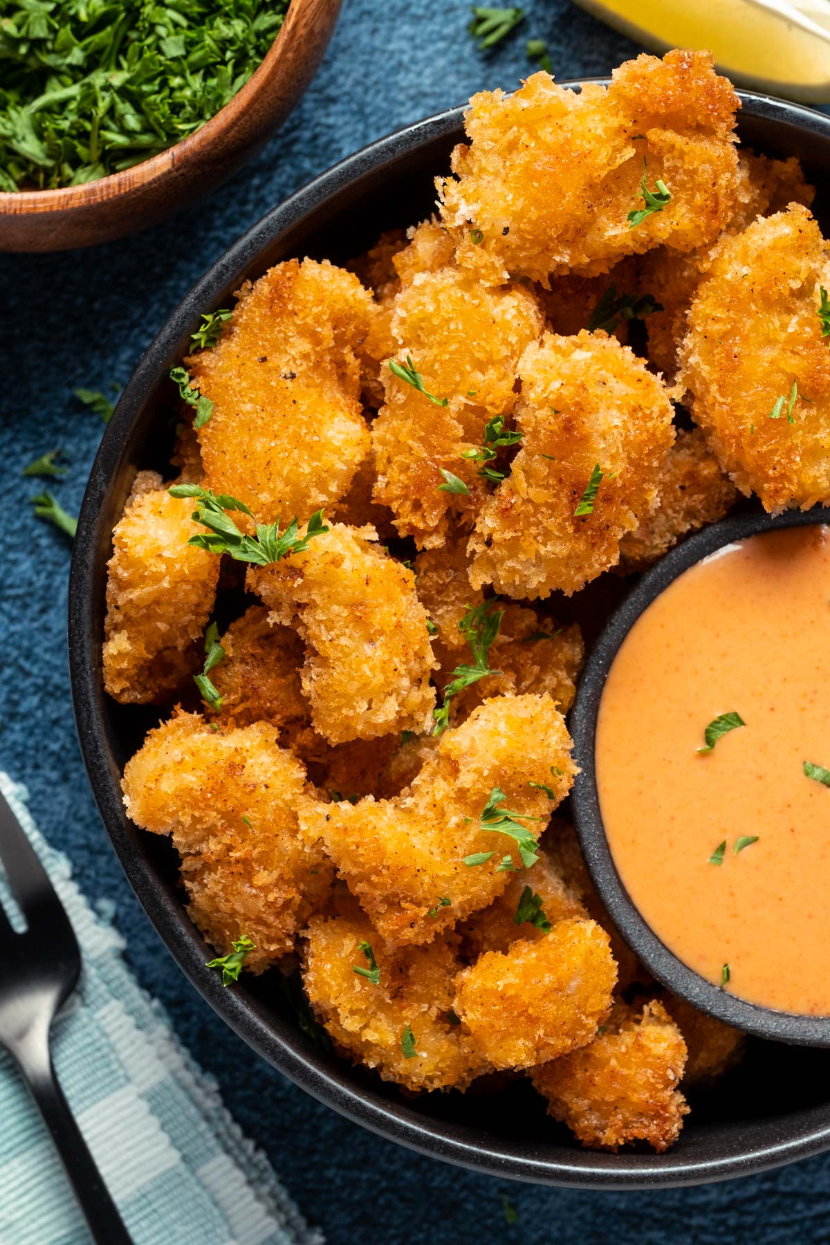 Vegan shrimp stacked up on a plate with a bowl of yum yum sauce on the side. 