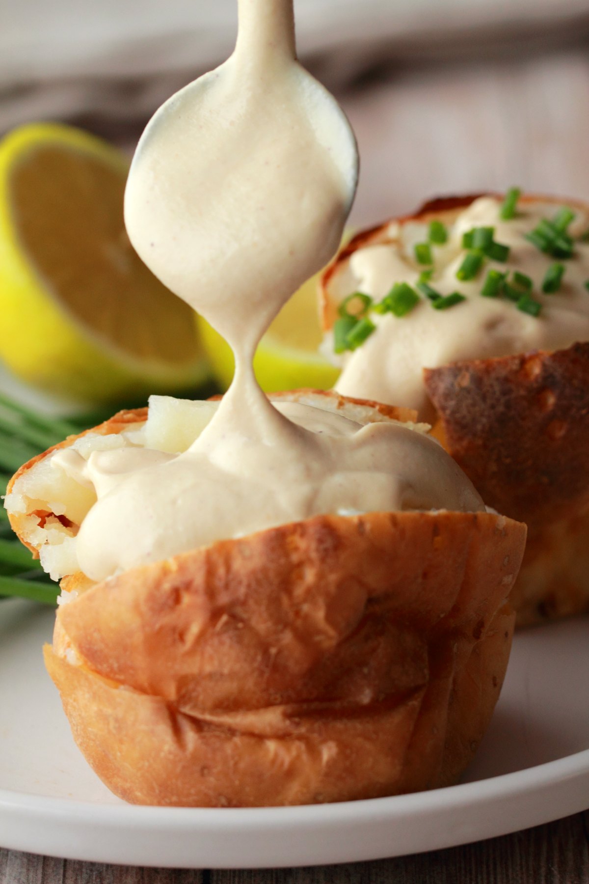 A large dollop of sour cream being placed onto a baked potato. 