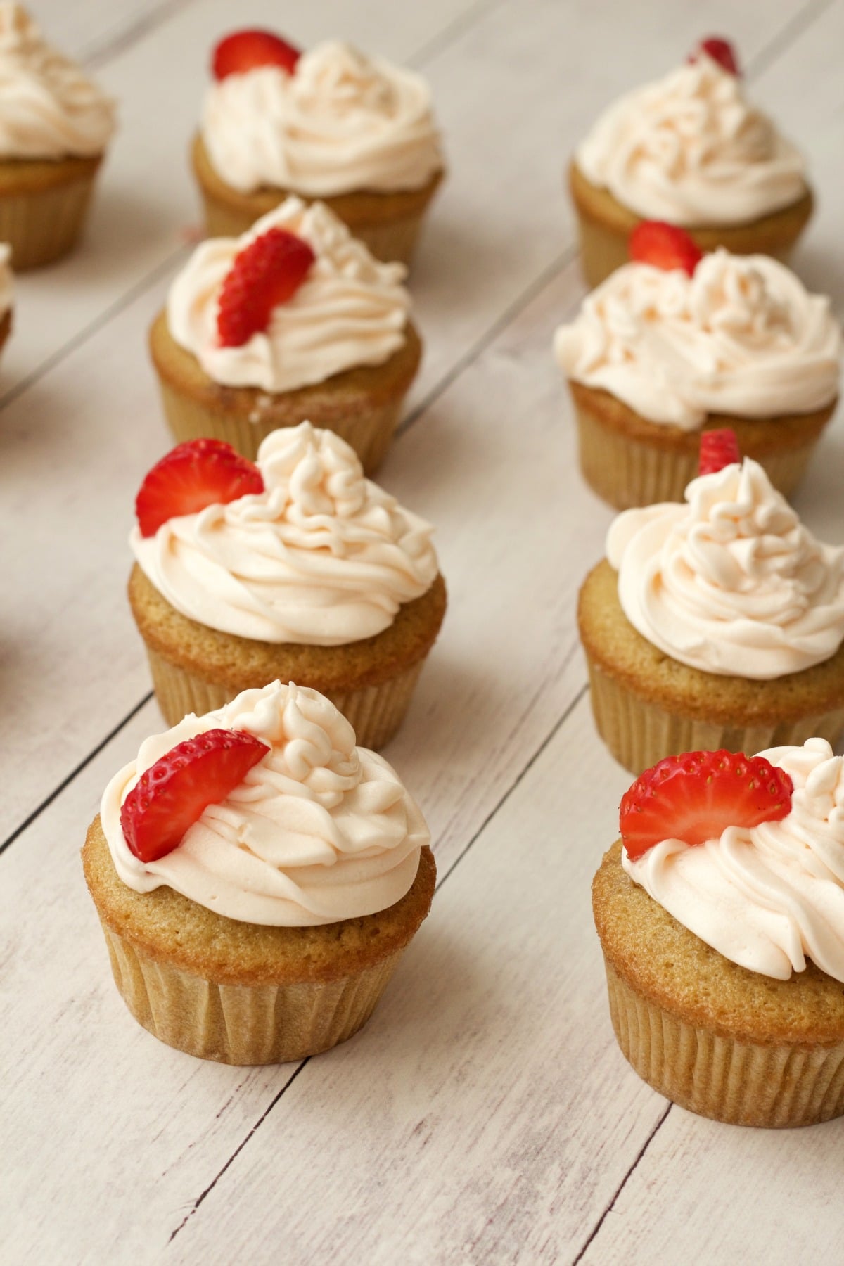 Vegan vanilla cupcakes with strawberry vanilla frosting and fresh strawberry decoration.