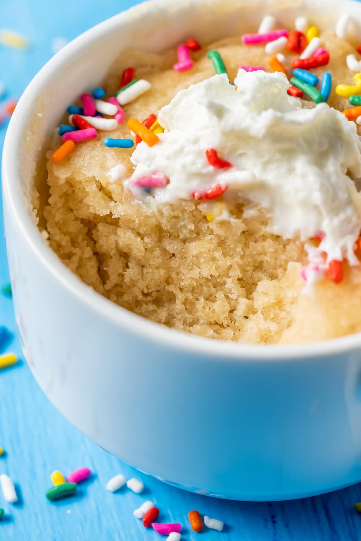 Vegan vanilla mug cake in a white mug with a spoonful taken out of it.